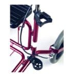 Human Care Cane Holder for Carl Oscar and Rebel — close-up of a red rollator side rail showing the upper black plastic clamp that grips the top of a cane plus the lower black cradle that supports the cane bottom near the wheel