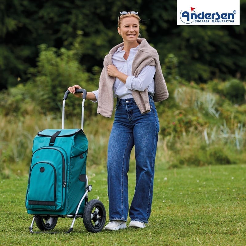 Woman pulling the petrol Andersen Royal Hydro 3.0 trolley across a lawn