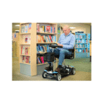 At the library Man seated reading a book in front of a library bookshelf