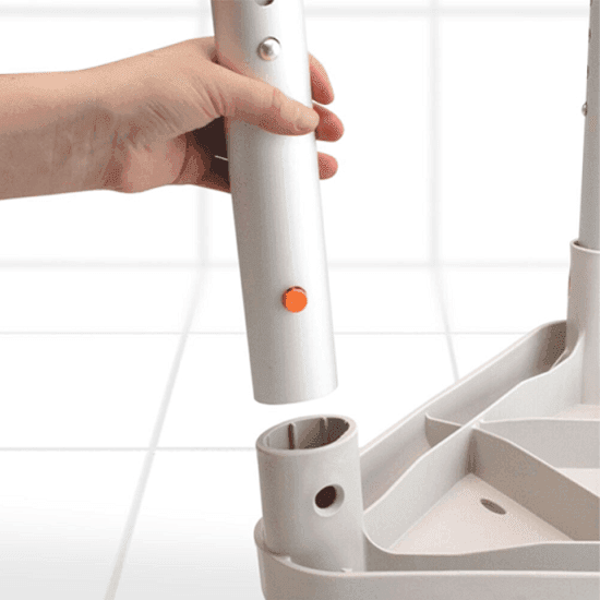 Hand pushing a stool leg into the triangular seat, orange spring button visible