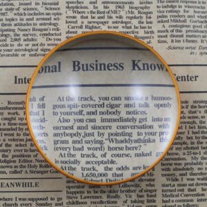 The magnifier on a newspaper page with the text under the lens magnified