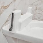 Close-up of the white drive unit with lifting arm at the back of the toilet