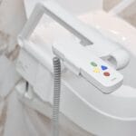 Close-up of the remote control with four coloured buttons attached to the armrest