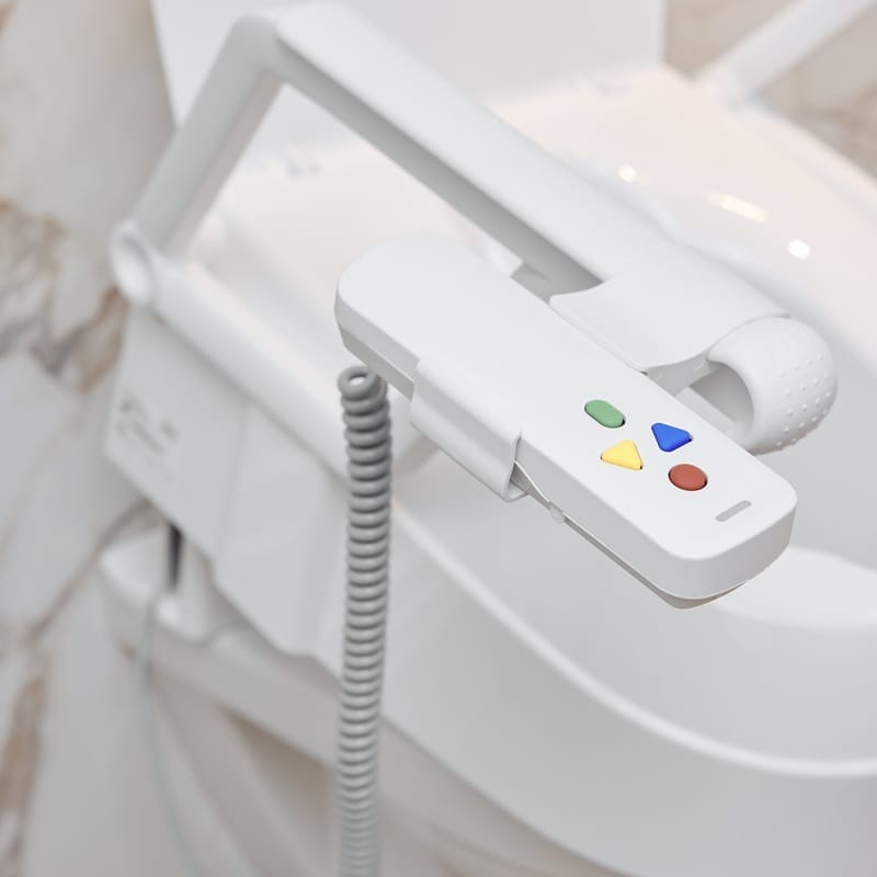 Close-up of the remote control with four coloured buttons attached to the armrest