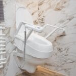 White toilet seat with armrests fitted on a wall-hung toilet