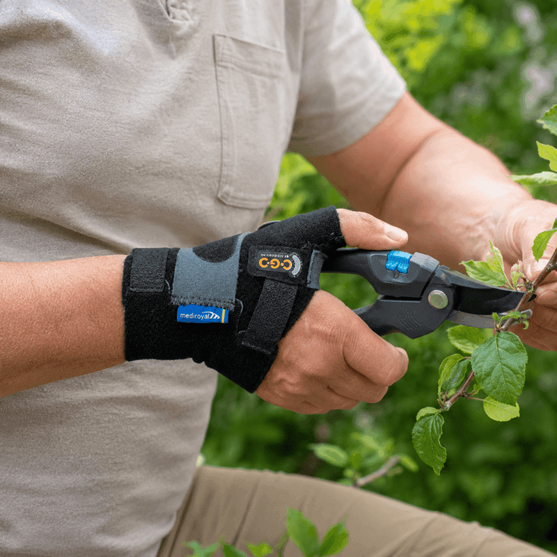 Man in the garden pruning branches with secateurs while wearing the thumb brace