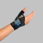 Mediroyal Neptune C-GO thumb brace Mediroyal Neptune C-GO thumb brace on the right hand with a grey Velcro strap over the thumb base