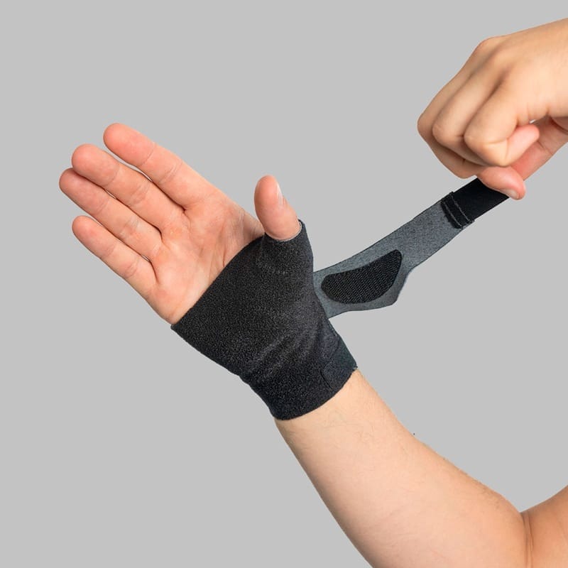 A hand pulling the grey strap around the wrist when putting the brace on